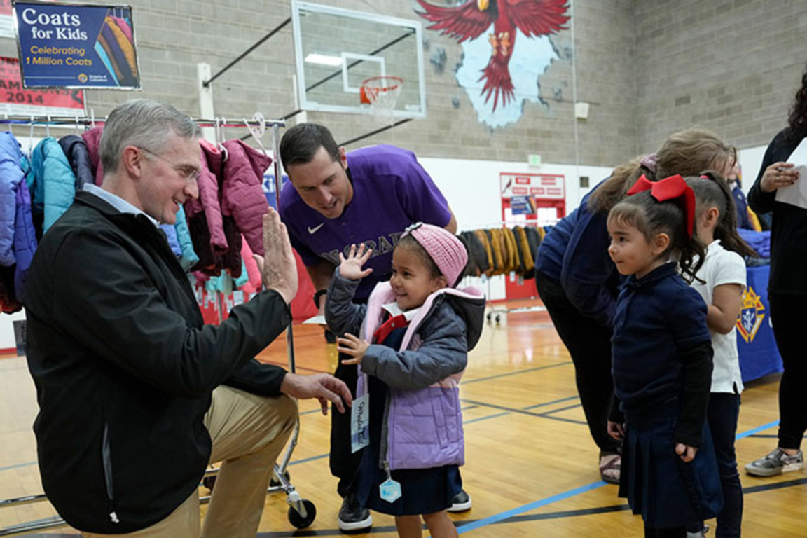Knights of Columbus members giving coats to children in the community